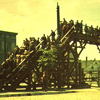 Menschen im Ghetto Łódź auf einer Holzbrücke.